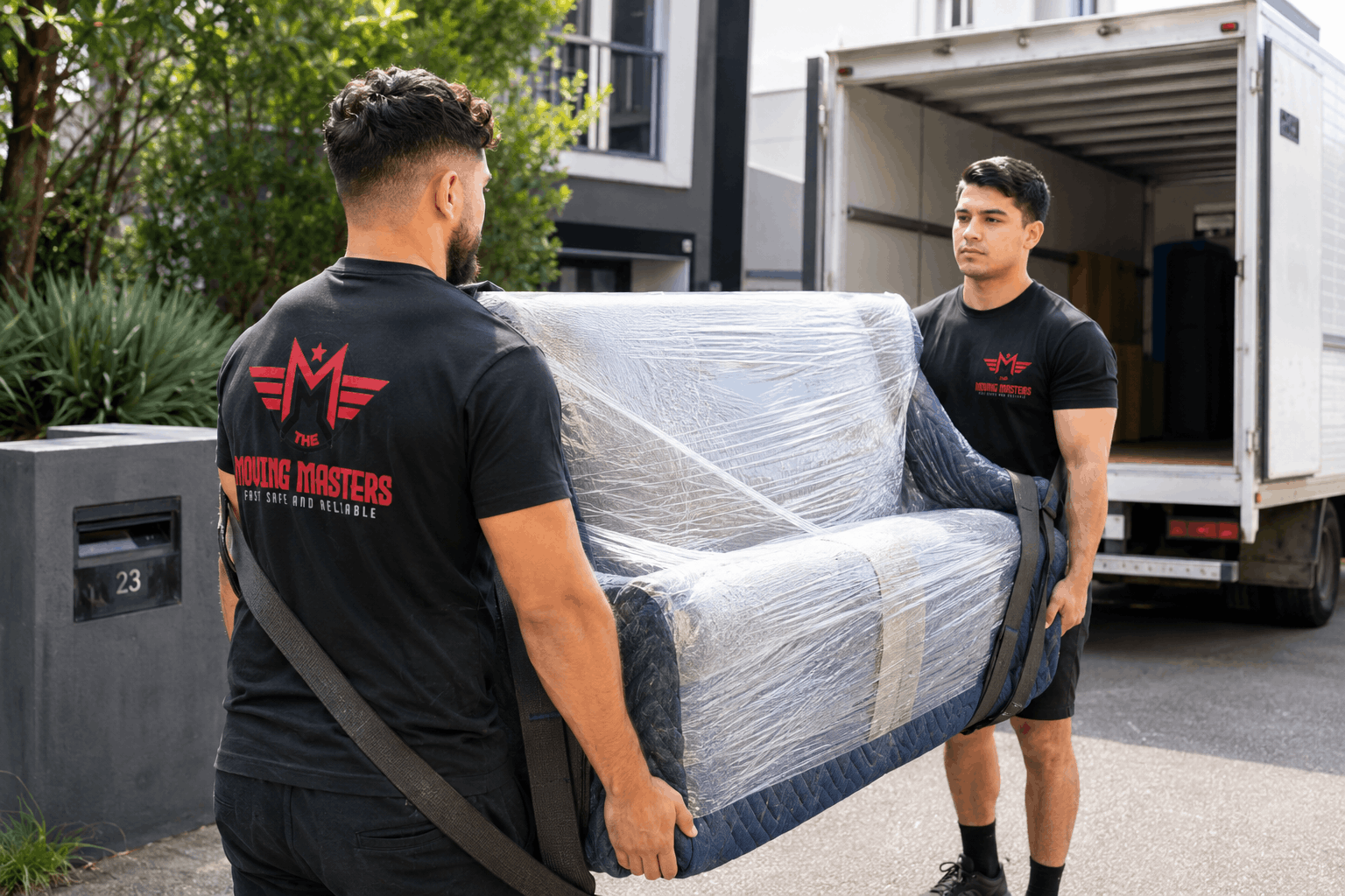 Moving Masters team wrapping and moving a sofa and dining furniture in an Auckland home